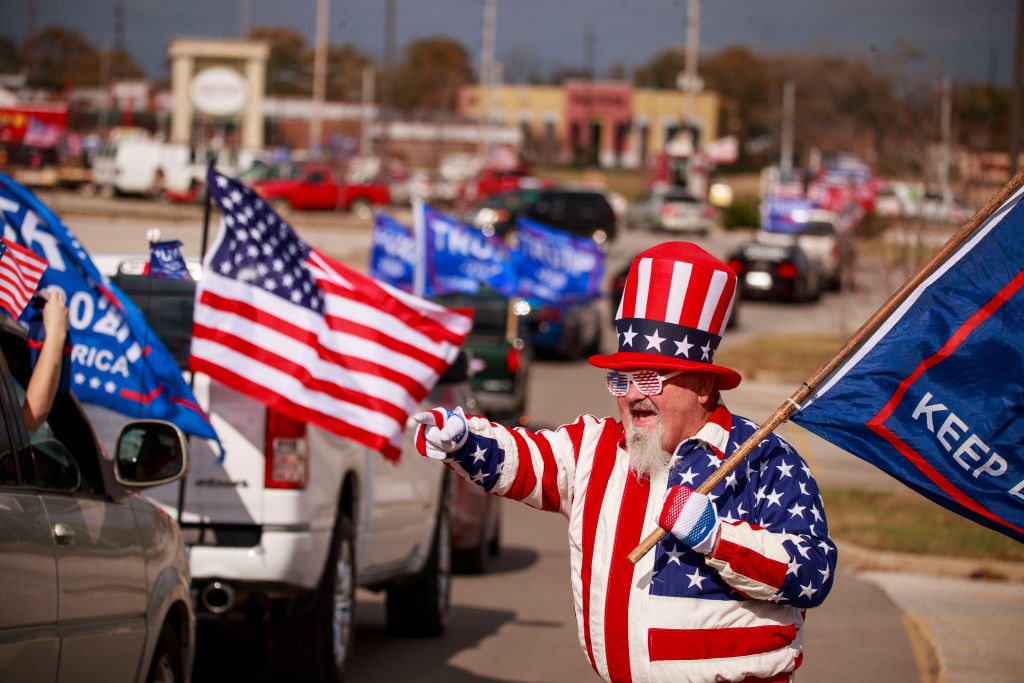 John Baker is dressed as Uncle Sam while waving to Trump...
