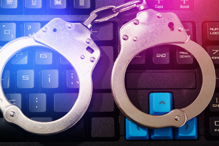 Metal handcuffs on computer keyboard, internet cybercrime