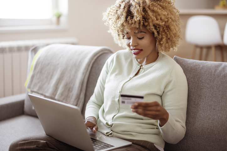 Black Woman Enjoying a Relaxing Online Shopping Session in Trendy Living Room
