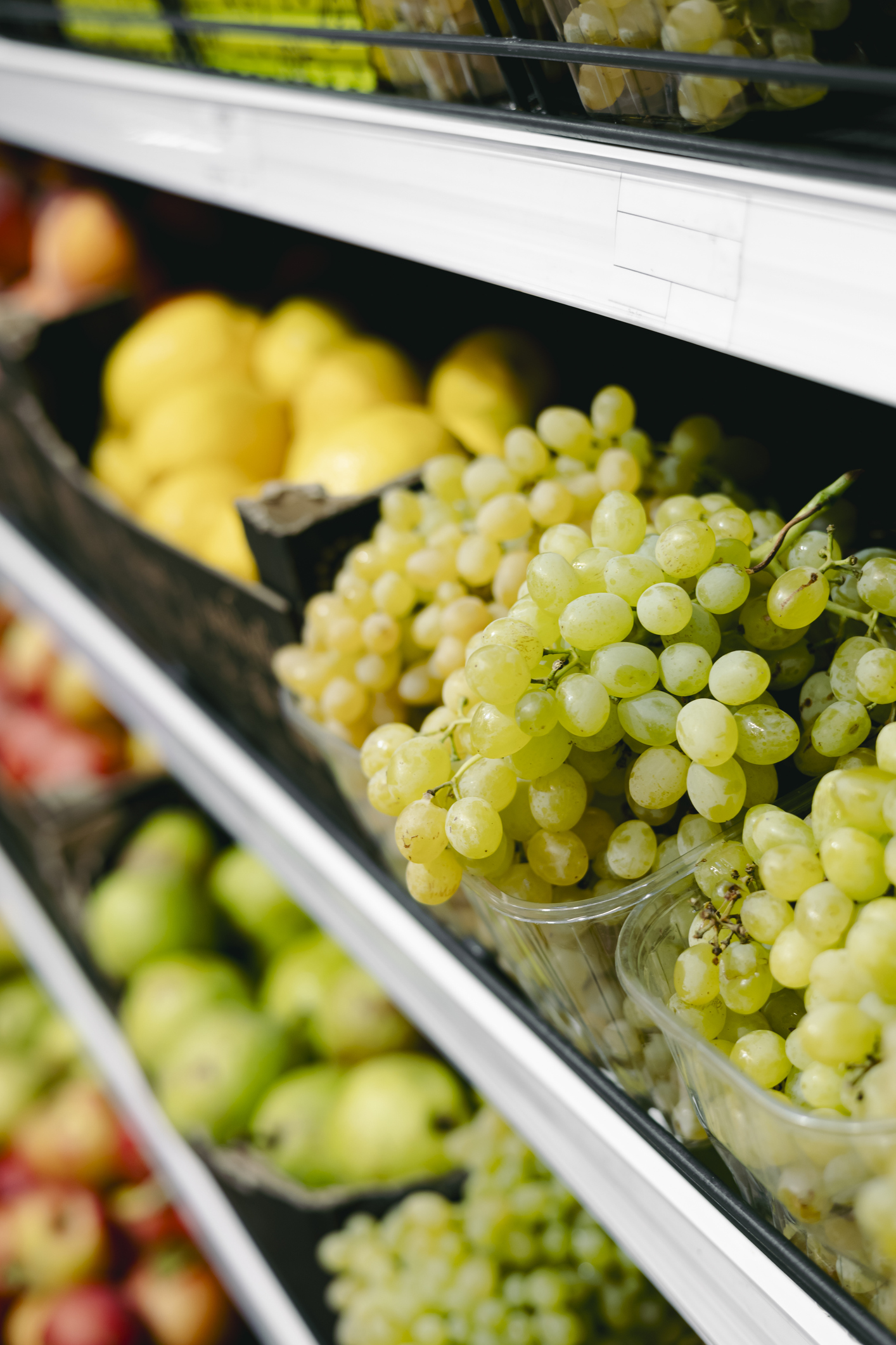 Close-up of supermarket grapes in trays on shelves, copy space.