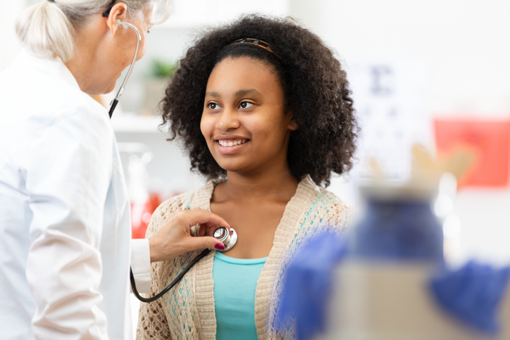 Young patient smiles during a doctor's examination with a stethoscope in a medical clinic.