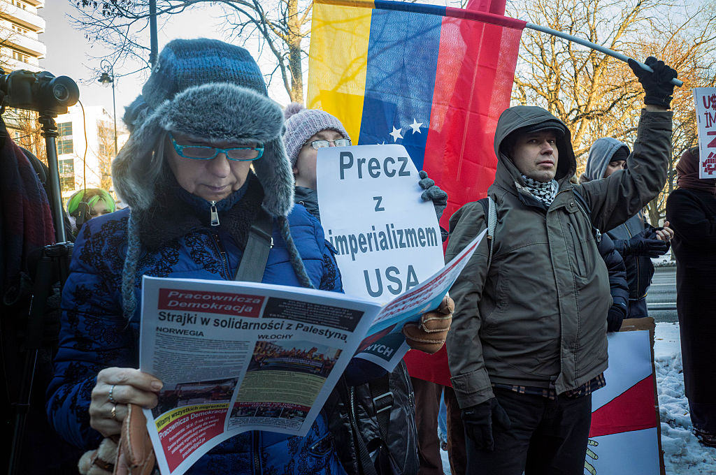 A protester waves a Venezuelan flag as another holds a...